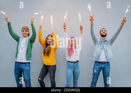 Groupe d'amis multiethniques qui se dansent avec des spameurs - des gens dansant Avec des barboteurs dans les mains - petit coup de jeune les gars tenant des lumières du bengale Banque D'Images