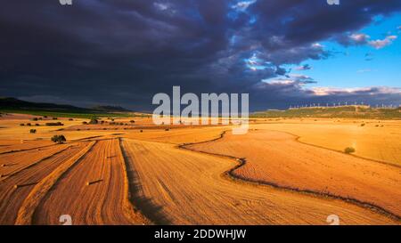 Une vue aérienne d'un paysage pluvieux et lourd de nuages au-dessus d'un incroyable champ doré lumineux avec des stocks de foin Banque D'Images