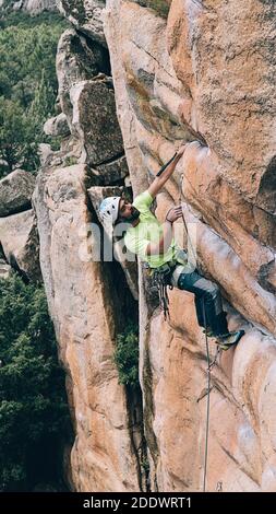 Homme barbu portant un casque et un harnais faisant de l'escalade. Banque D'Images