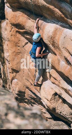 Femme sans visage portant un casque et un harnais de sécurité faisant de l'escalade dans la montagne. Banque D'Images