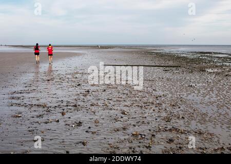 Deux femmes qui s'exécutent le long d'East Beach, en été, à Littlehampton, West Sussex, au Royaume-Uni, à marée basse Banque D'Images