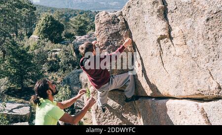 Photo d'un homme aidant un jeune garçon à monter un rocher dans la montagne. Banque D'Images