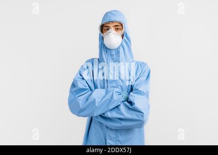 le médecin masculin porte une combinaison protectrice pour lutter contre la pandémie du coronavirus covid-2019. Combinaison de protection, lunettes de sécurité, gants, respirateur, sur un bac blanc Banque D'Images