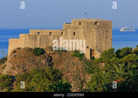 Un bateau de croisière naviguant devant le fort Lovrijenac du XIe siècle, alias la forteresse Saint-Laurent à Dubrovnik, en Croatie, à l'aube Banque D'Images