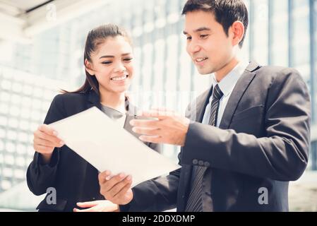 Femme d'affaires et homme d'affaires asiatiques discutant de documents à l'extérieur Banque D'Images