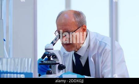 Un technicien de laboratoire expérimenté examine les échantillons et les liquides à l'aide d'un microscope dans un laboratoire équipé. Scientifique travaillant avec divers échantillons de bactéries, de tissus et de sang, recherche pharmaceutique pour les antibiotiques Banque D'Images