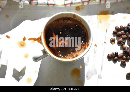 Cube de sucre tombant dans une tasse de café/UN cube de sucre déposé dans une tasse de café noir. Banque D'Images