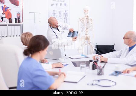 Médecin expert en radiographie pendant un séminaire médical pour le personnel médical dans la salle de conférence. Thérapeute en clinique parlant avec des collègues de la maladie, professionnel de la médecine Banque D'Images