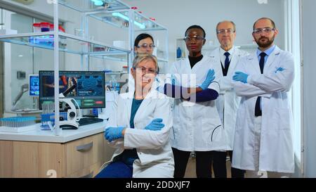Une équipe multiethnique de scientifiques expérimentés regardant la caméra dans un laboratoire moderne équipé. Groupe de médecins examinant l'évolution du virus avec des outils de haute technologie et de chimie pour la recherche scientifique, le développement de vaccins de covid19 Banque D'Images
