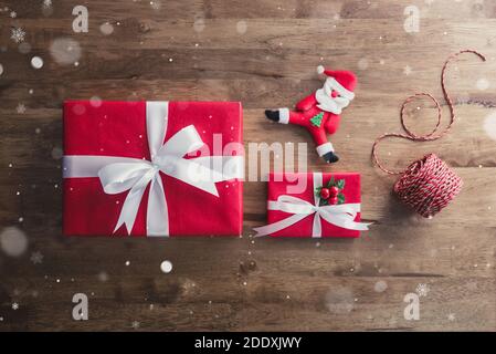 Vue de dessus des boîtes-cadeaux de Noël rouges colorées avec poupée du Père Noël et ficelle de décoration sur fond de table en bois, vue de dessus Banque D'Images