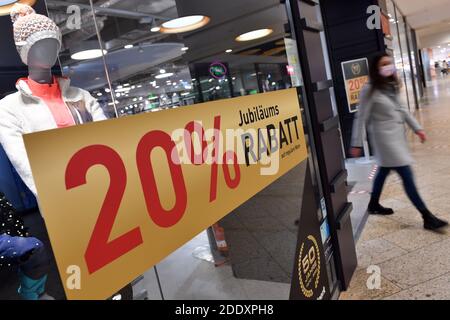 Sujet photo NOIR VENDREDI 26 novembre 2020. Une jeune femme avec masque, masque vient d'un magasin de mode. À côté, il y a des affiches et des étalages SOLDE, RABAIS. Pandémie, verrouillage, shutdown, valeur de l'incidence. MODÈLE DISPONIBLE ! | utilisation dans le monde entier Banque D'Images