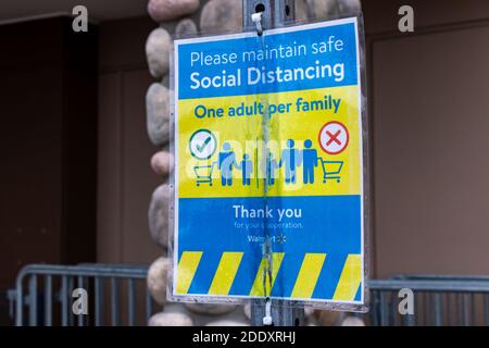 Courtenay, Canada - 21 novembre 2020 : vue sur l'affiche Veuillez maintenir une distance sociale sécuritaire, un adulte par famille à l'entrée du magasin Walmart Banque D'Images