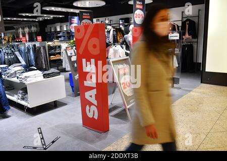 Sujet photo NOIR VENDREDI 26 novembre 2020. Une jeune femme avec masque, masque vient d'un magasin de mode. À côté, il y a des affiches et des étalages SOLDE, RABAIS. Pandémie, verrouillage, shutdown, valeur de l'incidence. MODÈLE DISPONIBLE ! | utilisation dans le monde entier Banque D'Images