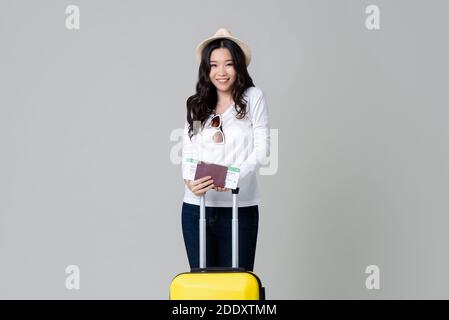 Bonne jeune femme asiatique touriste avec passeport de bagages et embarquement pass prêt pour voyager isolé sur fond gris studio Banque D'Images