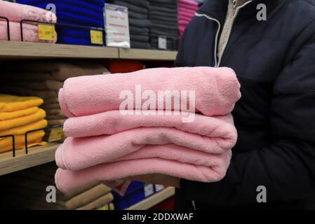 Un homme tient une pile de serviettes dans un magasin. Articles d'hygiène, serviettes de bain rose moelleuses dans le supermarché Banque D'Images