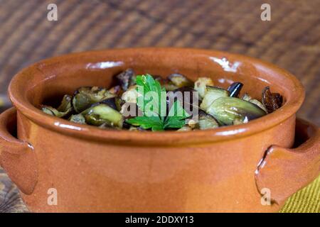 Aubergine coupée en dés dans une petite casserole sur fond de bois. Banque D'Images