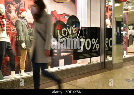 Sujet photo NOIR VENDREDI 26 novembre 2020. Une jeune femme avec masque, masque passe devant la fenêtre d'un magasin de mode. Un coeur noir est orné sur la fenêtre du magasin, J'AIME LE VENDREDI NOIR! Pandémie, verrouillage, shutdown, valeur de l'incidence. MODÈLE DISPONIBLE ! | utilisation dans le monde entier Banque D'Images