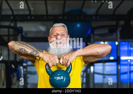 Homme de fitness senior faisant des exercices de cloche de bouilloire dans la salle de gym - Former des hommes matures dans le centre du club de bien-être Banque D'Images