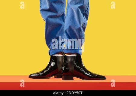 Jeunes hommes mode jambes en jeans bleus et bottes noires au sol rouge Banque D'Images