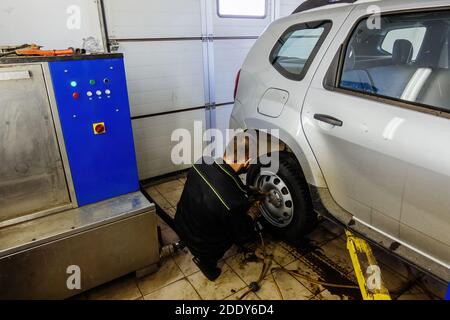 Un mécanicien change la roue d'une voiture dans un atelier d'entretien automobile Banque D'Images