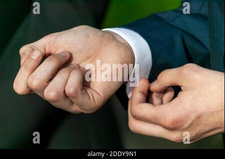 Adulte homme dans un costume de mode habillé ajustement et fixation de sa chemise bouton de manche à un mariage, photo de stock image Banque D'Images