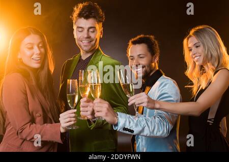 des amis multiculturels heureux tenant des verres de champagne et se clinquant noir Banque D'Images