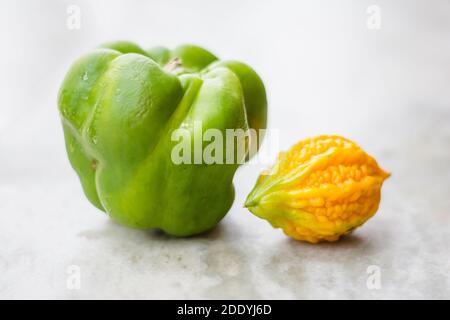 gourde jaune amer entre le capsicum vert avec un fond isolé, impair dehors Banque D'Images