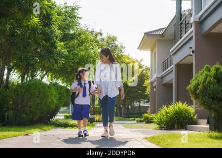 Bonne mère asiatique et fille élèves de l'école primaire marchant à l'école dans la routine de l'école du matin pour la journée dans la vie se préparer à l'école. Banque D'Images