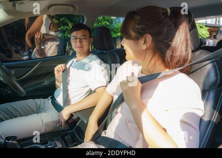 Les jeunes couples bouclent les ceintures de sécurité dans leur toute nouvelle voiture avant le voyage en toute sécurité. Banque D'Images