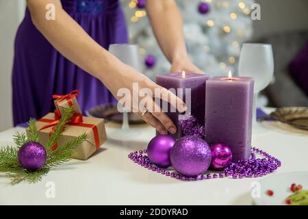 Fille fait la décoration de table de Noël avec des cadeaux et des bougies pourpres. Haute qualité Banque D'Images