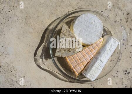 Assortiment de différents types de délicieux fromages dans une assiette en verre sur une table en pierre. Vue de dessus. Banque D'Images