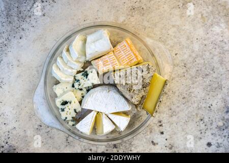 Assortiment de différents types de délicieux fromages dans une assiette en verre sur une table en pierre. Vue de dessus. Banque D'Images