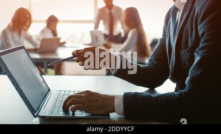 Tenant un stylo mâle freelancer pointant l'écran d'ordinateur montrant son collègue les mises à jour qu'il a fait. Homme d'affaires travaillant sur un ordinateur portable dans un bureau moderne Banque D'Images