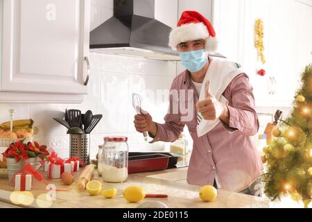 Homme cuisant des desserts à la maison avec un masque pour Covid-19 les vacances de noël. Composition horizontale. Banque D'Images