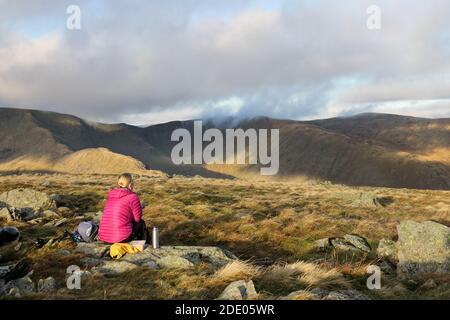 Walker en profitant d'une pause et de la vue sur Riggindale vers Kidsty Pike et High Raise de Branstree, Lake District, Cumbria, Royaume-Uni Banque D'Images