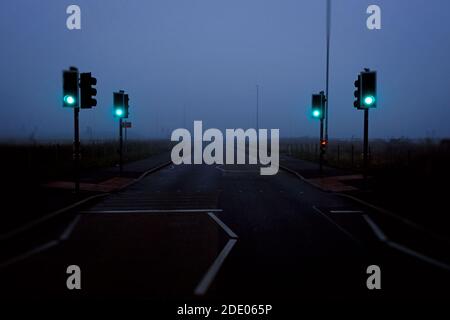 Feux de signalisation verts sur une route à l'atmosphère brumeuse à Bingham, dans le Nottinghamshire, en Angleterre. Banque D'Images
