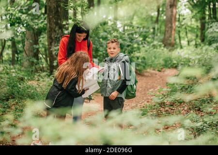 Belle mère avec deux enfants se promo dans la forêt, en utilisant une carte et en planifiant une randonnée. Bonne famille s'amuser ensemble.Selective Foc Banque D'Images