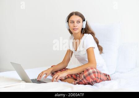 Jeune femme dans un casque étudiant en ligne, travaillant à la maison à l'aide d'un ordinateur portable Banque D'Images