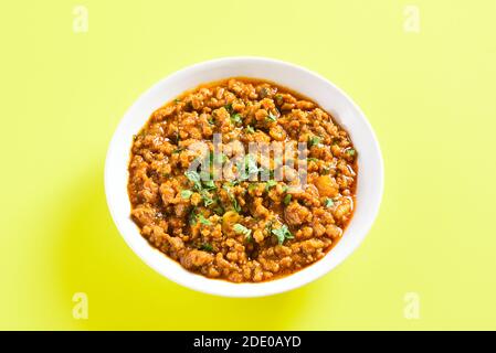 Vue rapprochée du curry de keema dans un bol sur fond jaune avec espace de copie. Plat de style indien et pakistanais. Banque D'Images