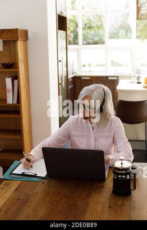 Femme caucasienne âgée utilisant un ordinateur portable et portant un casque Banque D'Images