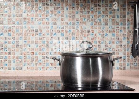 vieux pot en acier fermé sur poêle en céramique noire dans la table à la cuisine maison Banque D'Images