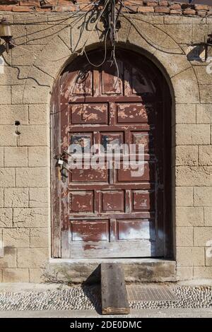 Vieux brun vieilli peint arqué portes en bois sur la façade de la maison en pierre coupée abandonnée, vieille ville de Rhodes, Rhodes, Grèce Banque D'Images