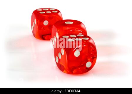 Dés en acrylique rouge transparent pour les jeux. Trois dés translucides de jeu sur fond blanc, macro gros plan haute résolution. Banque D'Images