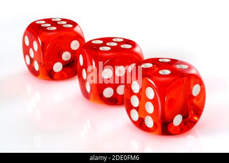 Dés en acrylique rouge transparent pour les jeux. Trois dés translucides de jeu sur fond blanc, macro gros plan haute résolution. Banque D'Images