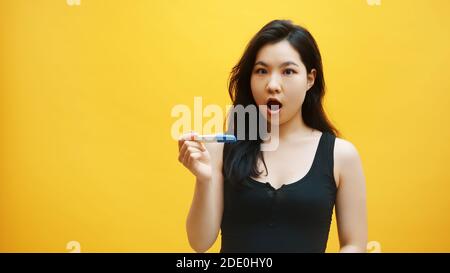 concept de grossesse non désirée. jeune femme asiatique impatiente regardant le test de grossesse en attente de résultats. . Photo de haute qualité Banque D'Images