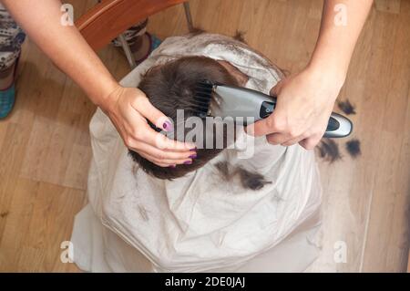 Gros plan sur les mains de la femme coupe les cheveux de l'enfant garçon à la maison Banque D'Images