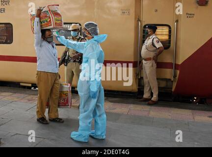 Mumbai, Inde. 27 novembre 2020. Un agent de santé vêtu d'un vêtement de protection vérifie la température corporelle d'un homme à la gare ferroviaire du Terminus de Bandra.les passagers voyageant du Rajasthan et du Gujarat ont été soumis à un contrôle de température à leur arrivée à la gare et, s'ils étaient suspects, ont été soumis à un test d'écouvillonnage dans les locaux de la gare. Crédit : SOPA Images Limited/Alamy Live News Banque D'Images