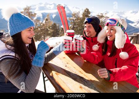 Groupe d'amis appréciant le vin chaud chaud au café de la station de ski. Banque D'Images