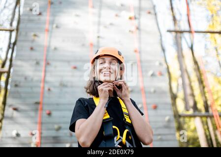 Portrait d'une jeune femme bien équipée debout devant du mur d'escalade au parc d'attractions Banque D'Images