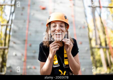 Portrait d'une jeune femme bien équipée debout devant du mur d'escalade au parc d'attractions Banque D'Images